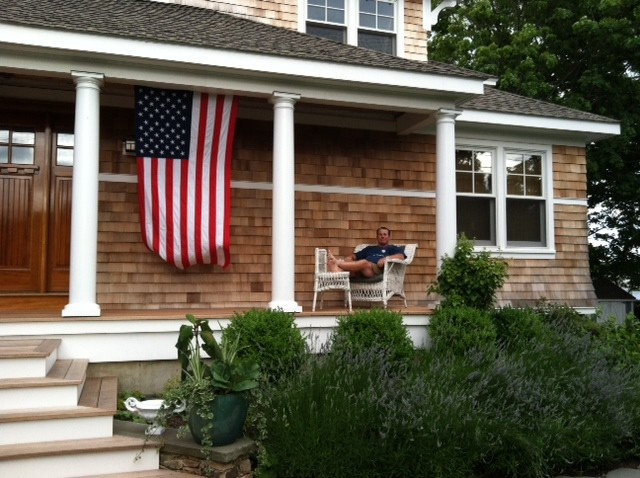 Image of an American flag hanging vertically on a porch. 