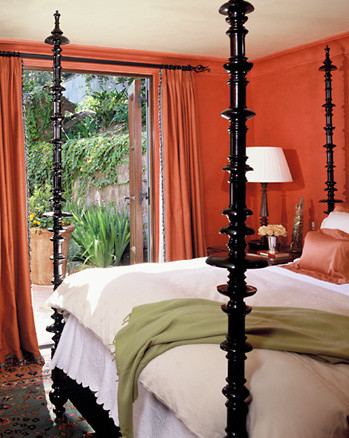 Orange walls emphasize the extreme height and turned shapes of dramatic bed 