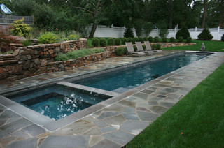 Small lap pool with spa surrounded by stone deck.