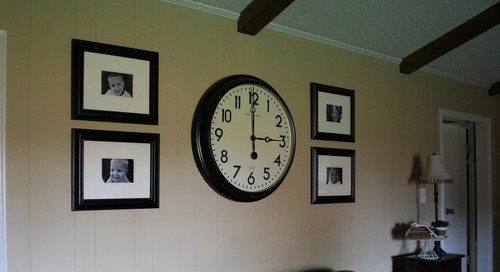 wall clock between artwork, analog wall clock