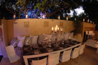 Outdoor dining room with elegant table setting and lots of candles.