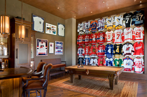 A media and game room outfitted with great lighting and an incredible hockey jersey collection. Photo credit: Traditional Family Room by Scottsdale Architects & Building Designers Esther Boivin Interiors