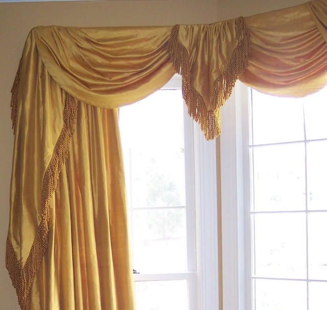 Silk swags and cascades over drapery panels trimmed with bullion trim.