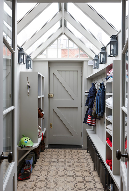 Use outdoor wall lights in your mudroom to transition from outdoor to indoor. Photo credit: Transitional Entry by London Interior Designers & Decorators Charlotte Crosland Interiors