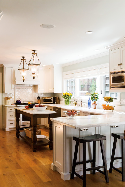 A white kitchen with a wood and white kitchen island and wood stools.